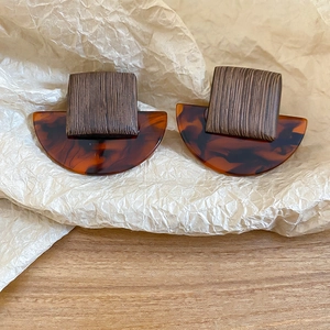 Detail of vintage square wood and amber resin earrings on elegant beige textured paper