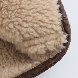 Detailed close-up of soft beige faux shearling lining on a vintage brown leather jacket