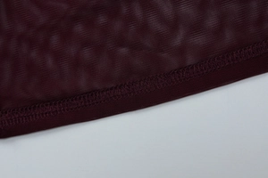 Détail de la texture en maille rouge foncé et des coutures de l'ourlet de la robe courte