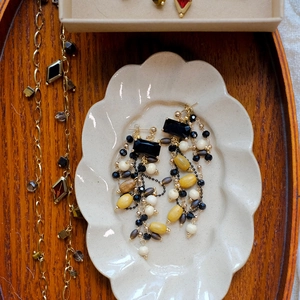 Detail view of retro wooden bead tassel earrings and gold chain necklace set in ceramic dish