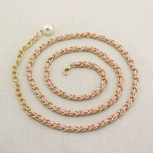 Detail of gold metal chain woven with pink cord and a large pearl pendant clasp