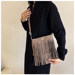 Detail showing the beige fringe crossbody bag with suede texture and metal buckle