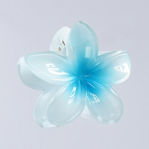 Detail showing the sea-blue gradient plumeria hair claw with high-gloss polished finish