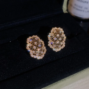 Vue détaillée de boucles d'oreilles ovales évidées avec zircons sur velours noir luxueux