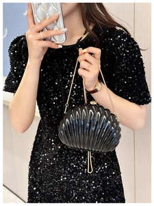 Detail of shell-shaped black acrylic evening bag with gold chain and metal clasp