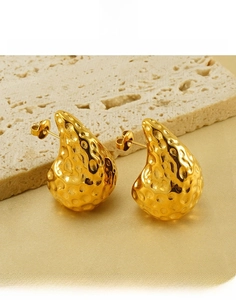 Macro detail of 18K gold-plated teardrop earrings with textured hammered finish on silk