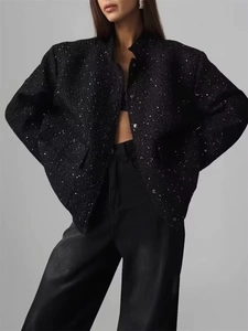 Detail of black sequined tweed jacket with standing collar and subtle shimmer texture