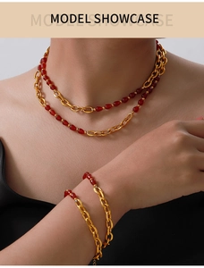 Detail of elegant gold double-layer necklace and bracelet set with red gemstone drops