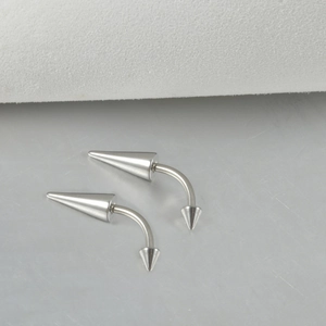 Close-up of polished stainless steel curved barbell with double cone spikes on metal base