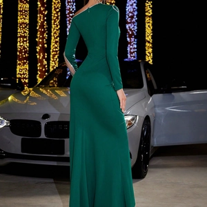 Close-up of sparkling rhinestone trim on an emerald green one-shoulder evening dress