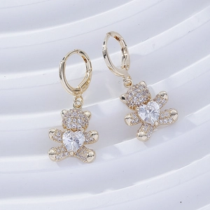Detailed close-up of gold bear earrings featuring micro-pave crystals and heart-shaped zircon