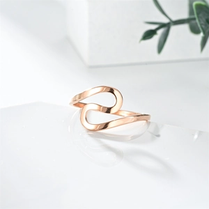 Detail of rose gold wavy ring with polished finish against a minimalist white background