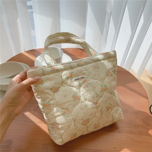 Détail du sac matelassé à fleurs avec étiquette Simple Wish posé sur une table en bois