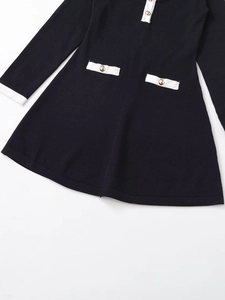 Detail view of the soft knitted fabric with gold buttons on this black and white dress