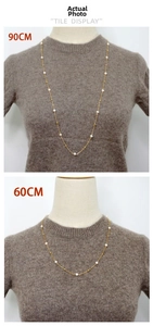 Comparaison de colliers de perles de 60 cm et 90 cm sur un pull en tricot foncé