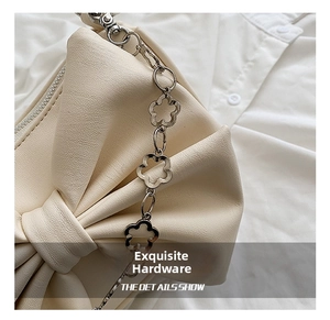 Detail of cream leather bag featuring a large bow and silver flower-shaped hardware chain