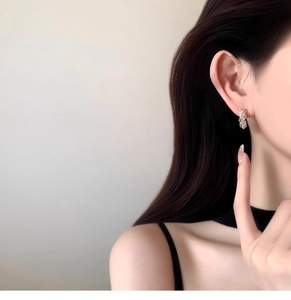 Close-up of elegant silver C-shape earrings with zircon inlay worn by a female model