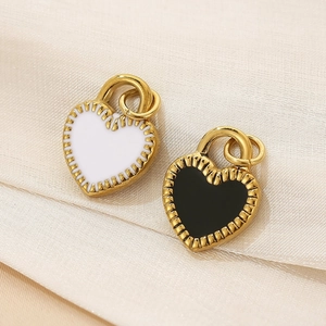 Detailed close-up of heart-shaped pendants with black and white enamel in gold finish