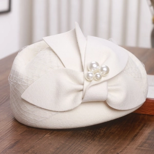 Detail of white wool felt beret with elegant mesh veil and pearl-embellished bow