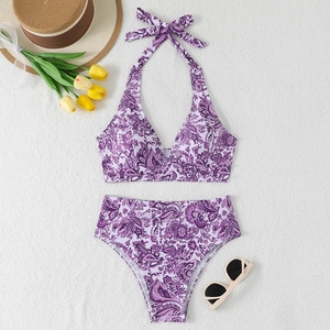 Detailed flat lay of purple paisley bikini with straw hat and yellow tulips