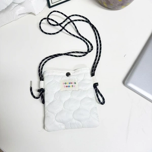 Close-up of white quilted mini bag with woven lanyard and snap button closure