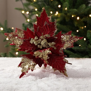 Red velvet Christmas flower with gold sequins and glitter on snowy background