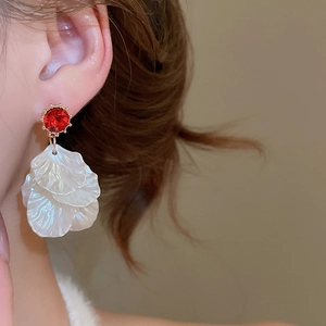 Detail of elegant red gemstone and white petal drop earrings on model for a stylish look