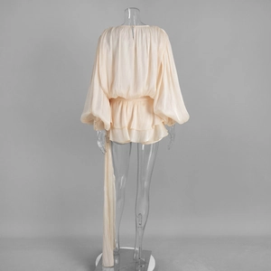 Detail view of the back of an apricot chiffon dress featuring ruffled hem and bow tie waist