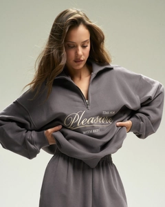 Detail of grey half-zip sweatshirt featuring Pleasure embroidery and ribbed cuffs