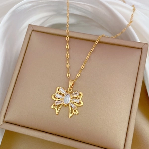 Detailed shot of gold bow necklace with clear cubic zirconia on beige jewelry box