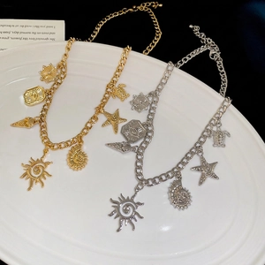 Gold and silver chunky charm necklaces with sea shells and starfish on white ceramic plate