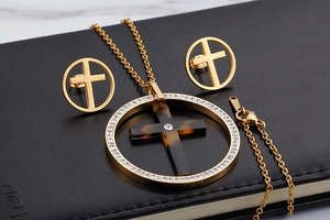 Detail of gold-plated stainless steel cross necklace set with tortoise resin and crystals