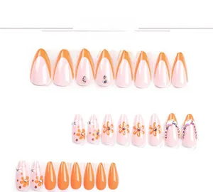 Détails de faux ongles amande orange et rose avec motifs marguerites et strass brillants