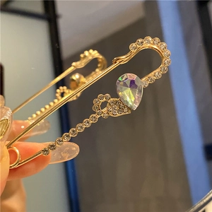 Macro detail of golden waist pin with teardrop iridescent stone and sparkling rhinestones