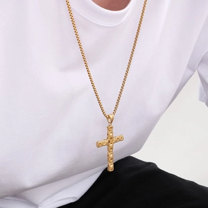 Close-up of a gold Byzantine chain and cross pendant necklace on a person