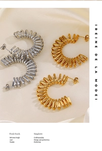 Detail of twisted spiral C-shaped earrings in gold and silver finish on silk fabric