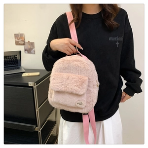 Detalle de mochila de felpa rosa mostrando textura suave y parche de buena suerte
