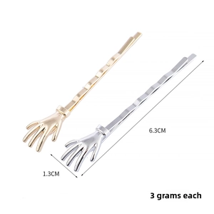Macro shot showing 6.3cm gold and silver skeleton hand hair clips with dimensions and weight