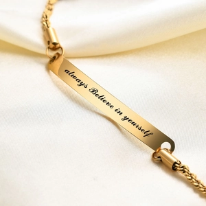 Detailed close-up of golden curved bar bracelet engraved with always believe in yourself
