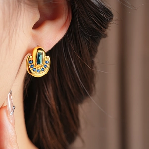 Gros plan de boucles d'oreilles vintage dorées avec zircons bleus sur un mannequin