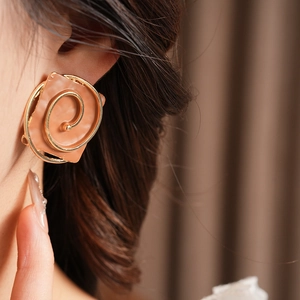 Close-up of vintage square orange earrings with golden spiral on model's ear