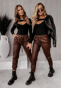Dettaglio dei jogger in ecopelle marrone con vita elastica e top nero con ritaglio