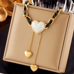 Detail of gold heart pendant with white gemstone and black leather woven chain
