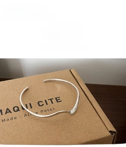 Dettaglio del bracciale rigido a onde minimalista in argento 925 su confezione regalo