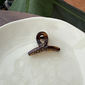 Detailed top view of a mini amber tortoiseshell hair claw on a white ceramic plate