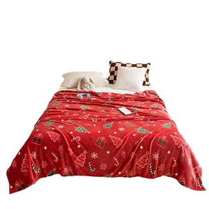 Thick red flannel Christmas blanket with festive holiday prints on a cozy double bed