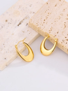 Detail of 18K gold plated stainless steel U-shaped earrings on beige porous stone