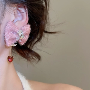Detail of pink fabric bow earring with crystal star and red heart pendant on model