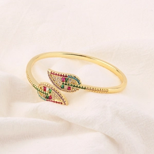 Macro view of gold-plated leaf-shaped cuff bracelet with vibrant multi-color zircons