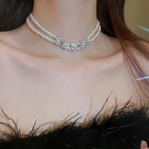 Double-layered pearl necklace with diamond flower charms worn on a model's neck